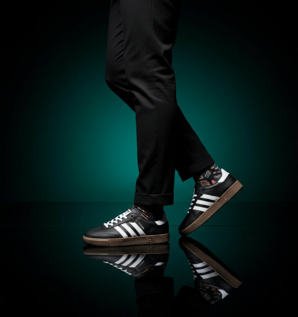 Black sneakers with white stripes and brown soles on a dark textured background, featuring the 'Friends' brand logo.